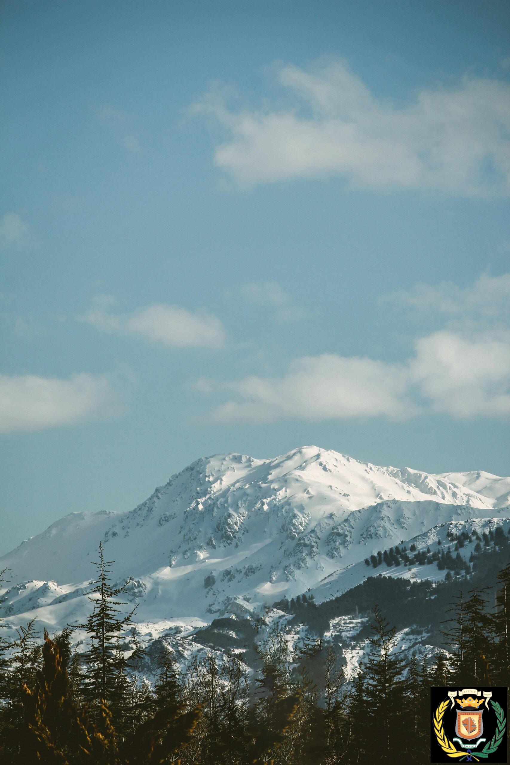 A picturesque snow-capped mountain range captured under a clear blue sky, epitomizing winter's beauty.