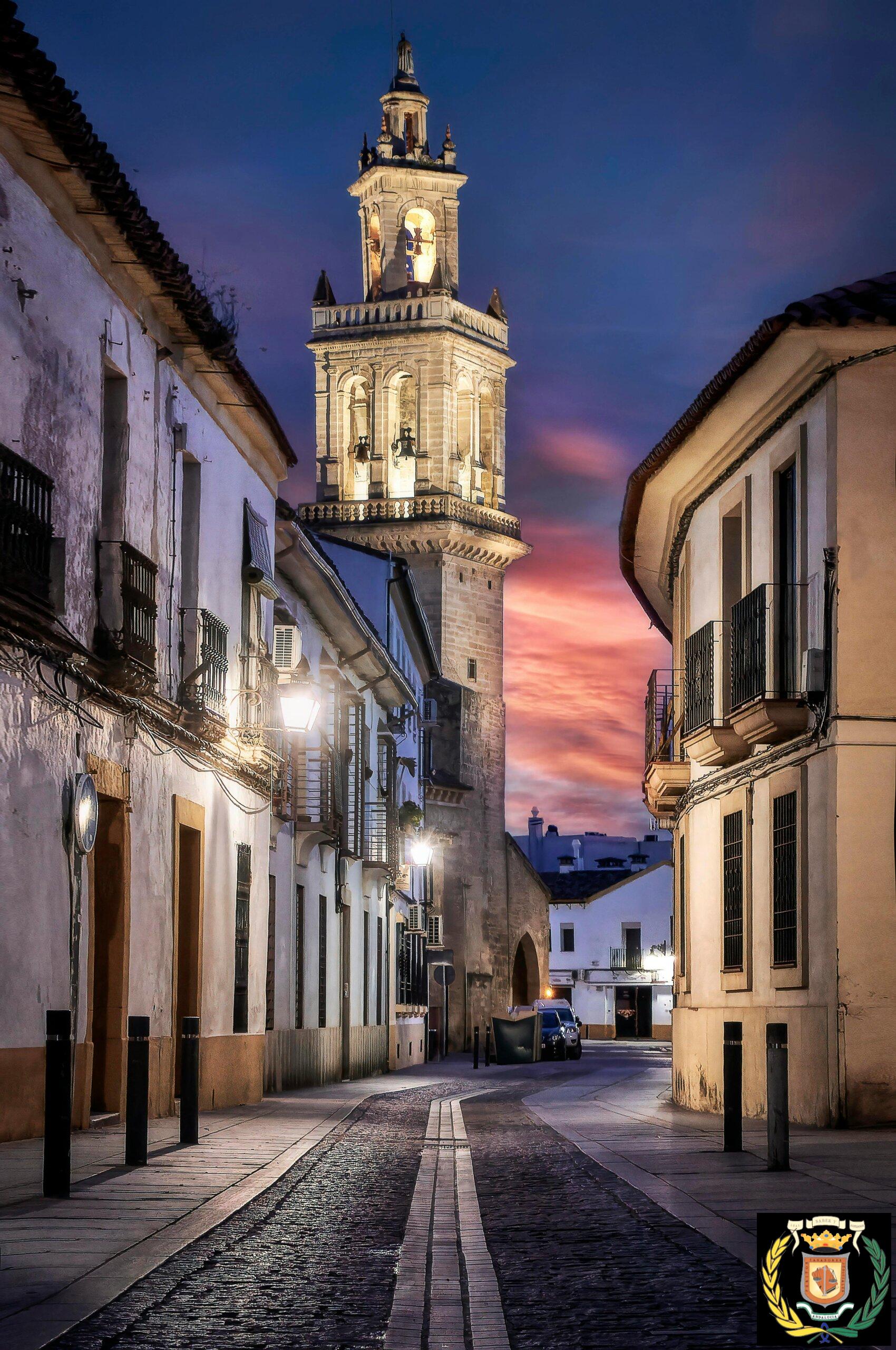 Capture of the illuminated bell tower on a cobblestone street in Córdoba during twilight.